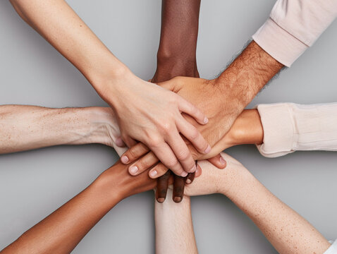 Photo of hands of different skin tones joined together in unity