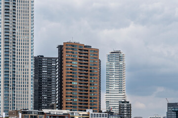 Tall high-rise buildings with varying architectural designs stand prominently under a cloudy sky, representing the dynamic and evolving nature of urban environments in Rotterdam