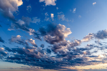Beautiful white puffy clouds against blue sky during dramatic sunset