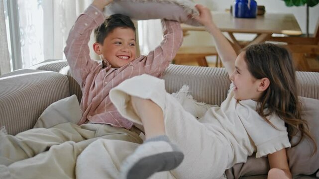 Funny kids pillows fighting at sofa closeup. Carefree little children having fun