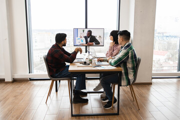 Coworkers collaborating during video conference meeting in modern office setting. Engaged in...