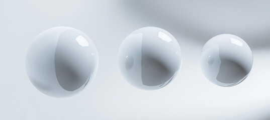 A close-up of three white spheres with rounded edges, suspended in the air against a clean background