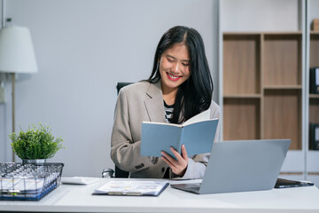 Female hand working search page on computer and writing on a notepad with a pen in the office. on the wooden desk there a graph business diagram.