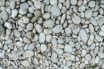gray pebbles round river bank, background stone light texture