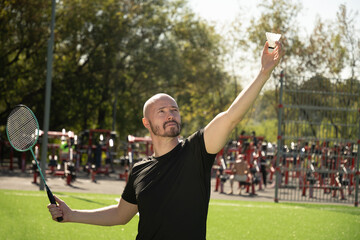 Man playing badminton on floor sport court in public park. Outdoors. Close up.