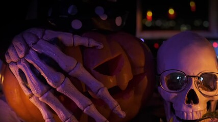 Dead hands touching pumpkins Jack Lantern, flashing inside, Halloween night spooky invitation background with human skull and candle.