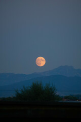 Big red moon rising above mountains in the sky