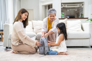 Asian family preparing school backpack together, mother, grandmother and girl child organizing...