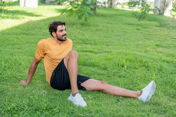 portrait young athletic sportsman relaxing on lawn in the park,after exercising