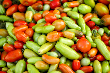 A vibrant and colorful background featuring a variety of tomatoes and plums in shades of green and red. rich textures and diverse colors of the fruits, creating  lively and visually appealing pattern