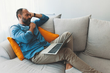 Fototapeta premium Man Relaxing on Couch with Laptop at Home