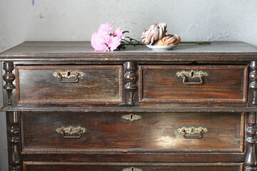 Still life with flowers and butterflies on an old chest of drawers on a blurred gray background