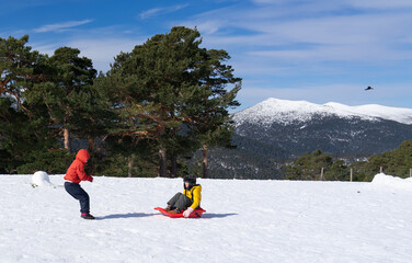 Two children playing with a sled on the snowy mountain. healthy lifestyle