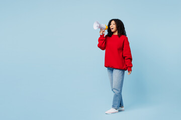 Full body little kid teen girl of African American ethnicity wear red sweatshirt hold in hand megaphone scream announces discounts sale Hurry up isolated on plain blue background. Childhood concept.