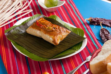 Beautiful Guatemalan food dish consisting of corn tamale, white bread, lemon and dried chili.