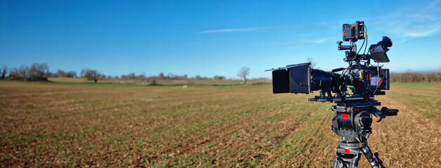 a professional video camera in a field shooting pictures for a documentary film.