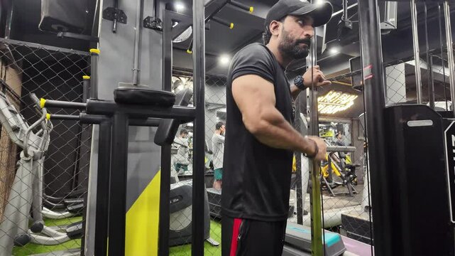 Young fit muscular man close up doing triceps pull down rope extension exercise in modern fitness center 