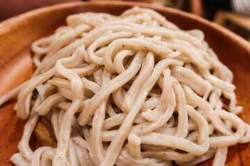 close up of cooked Japanese wheat noodles udon in a wooden plate 