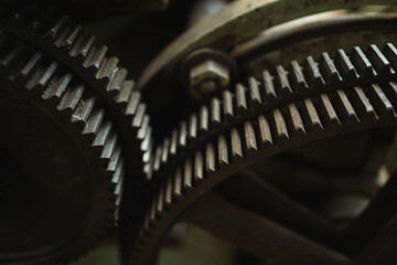 Fototapeta premium Two gears are shown in close up, one of which is missing a tooth. Concept of wear and tear, as the gears appear to be old and rusty. The close-up view emphasizes the details of the gears