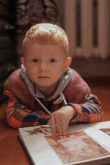 red haired child looking at photo album in old retro style apartment
