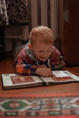 little child playing with a book
red haired child looking at photo album in old retro style apartment