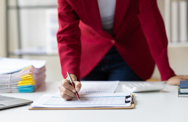Businesswoman working with documents is analyzing financial data statistically, calculating income and expenses, managing budgets and planning finances.