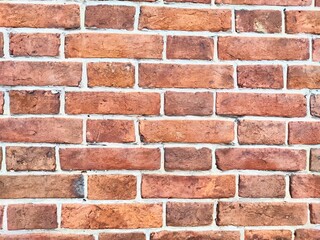 A close-up view of a textured red brick wall with varying shades of clay in daylight