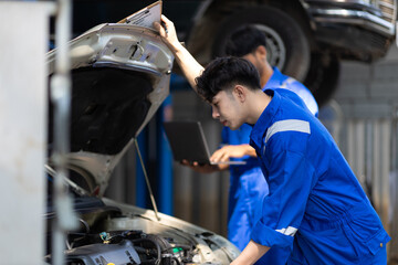 Auto mechanic is checking the engine system of a car in the garage.