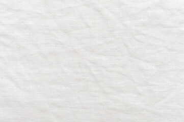 Close-up of a wrinkled white linen shirt. White textured background image.