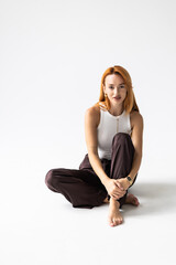 Fototapeta premium Happy young woman sitting on the floor on white background