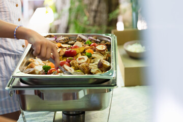 Delicious grilled chicken and fresh vegetables being served at a lively outdoor gathering during a sunny afternoon
