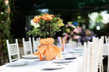Elegant dining setup with floral arrangements at an outdoor event in a garden setting during daytime