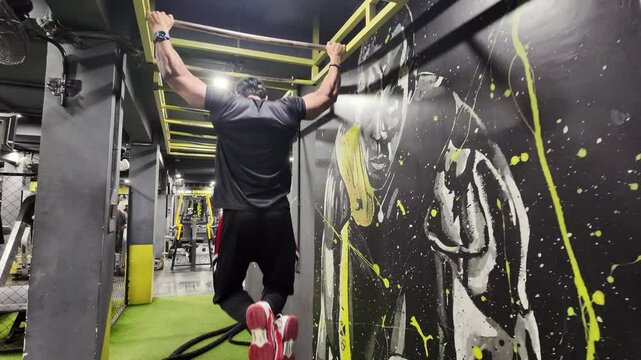 A man at the gym performing pullups on the horizontal bar