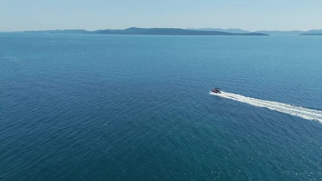 Small speedboat gliding through waves of Adriatic sea near Kornati archipelago, Croatia. Travel, tourism, vacation, free lifestyle and luxury concepts. Aerial chase drone shot. 4K 60FPS