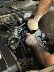 An experienced mechanic meticulously repairs a vintage car in a rustic, cluttered garage.