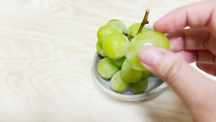 Eating seedless green grapes on a wood table