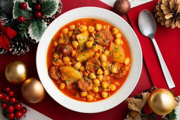 Delicious dish of braised chickpeas with spicy chorizo. Table with christmas decoration.