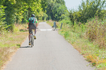Obraz premium Rear view of a cyclist riding on a rural road.