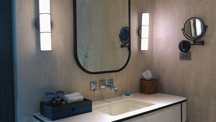 Modern bathroom with minimalist design, featuring large mirror, contemporary lighting, and neatly organized toiletries. Home Decor and Interior Design.