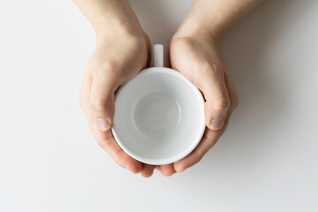 Close-up of a man's hand holding an empty white coffee cup.