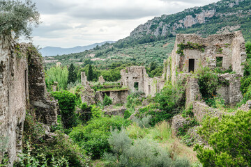 Ruins of an ancient city with crumbling walls and overgrown vegetation create hauntingly beautiful landscape. remnants of history are surrounded by lush greenery and mountains