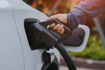 Hand is holding fast electric car charger green energy environment friendly driving vehicle...