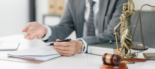 Legal professional discussing documents with gavel and scales of justice nearby.