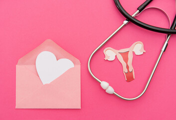 Stethoscope with uterus cutout and heart in envelope on pink background symbolizing women's health...