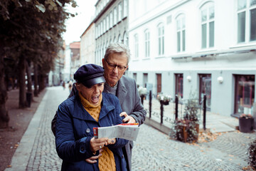 Senior couple laughing and exploring city with a map