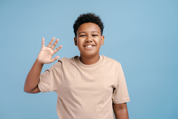 Portrait of emotional african teenager boy waving by hand looking at camera © Maria Vitkovska
