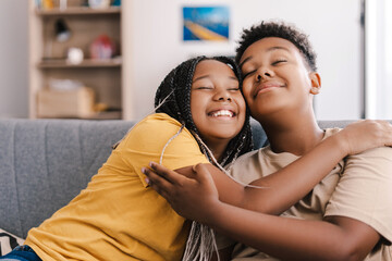 Obraz premium Two happy children hugging tightly on sofa