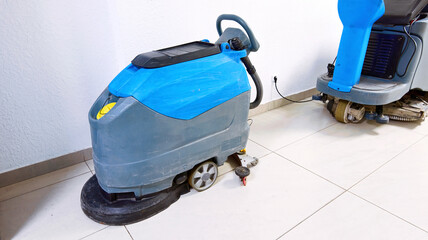Floor cleaning machine, electric floor scrubber stands at shopping mall at the electric point and charge battery. Floor sweeper machine.