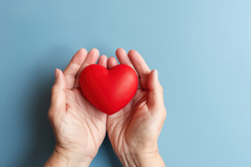 Red  heart in woman's hand support on aging a blue background for promoting health care campaign concept, Heart day, Hear attact, Valentine's day
