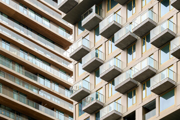 This image showcases a side view of a modern apartment building with balconies featuring glass railings, giving it an airy and contemporary look with clean lines and sharp angles in Rotterdam